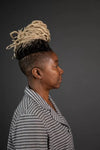 Person with styled hair and striped shirt against a dark background