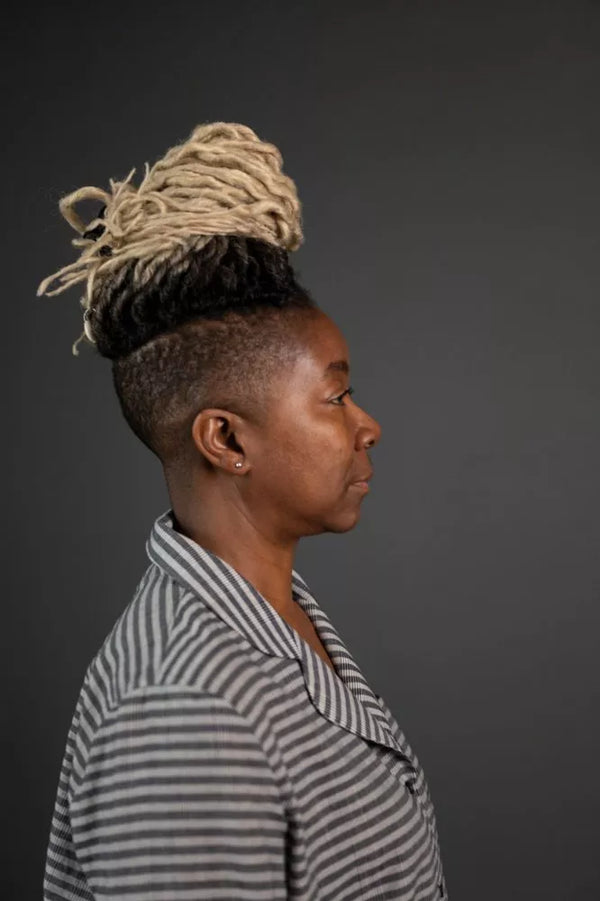 Person with styled hair and striped shirt against a dark background