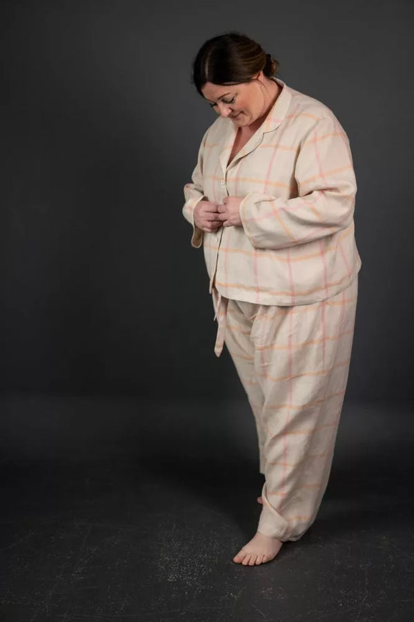 Woman wearing a beige plaid pajama set against a dark background