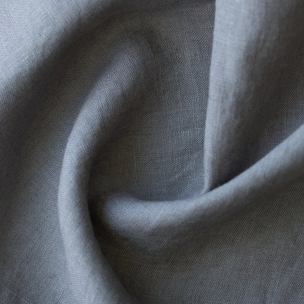 A close-up of draped light gray linen fabric showing its natural woven texture and soft folds.