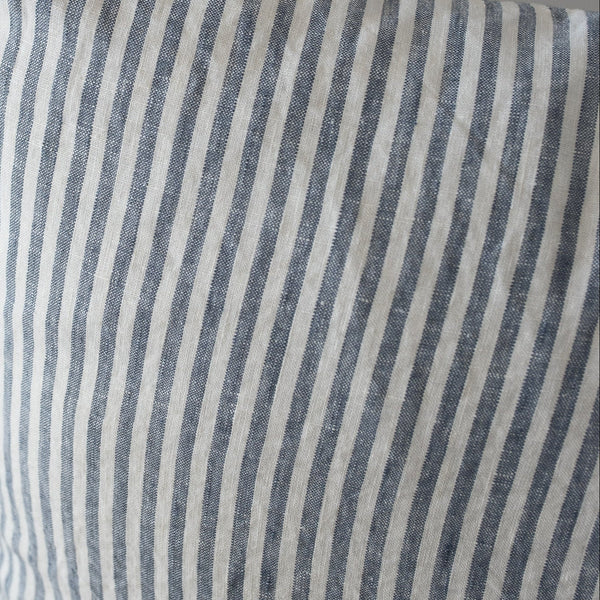 Striped blue and white pillow on a chair with a neutral background