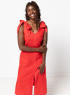 Woman wearing a red dress made using a style arc Esther woven dress sewing pattern with bow straps on a white background