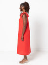 Woman wearing a red dressmade using a style arc Esther woven dress sewing patternwith bow straps on a white background