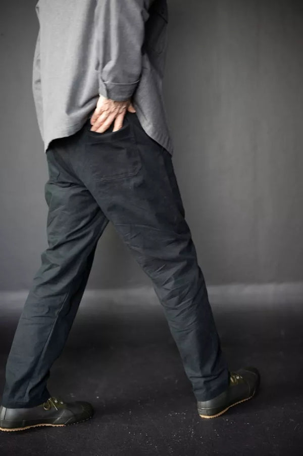 Person wearing dark The Elling Men’s Trouserand a light gray shirt against a plain background