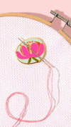 Embroidery hoop with floral design and pink thread on a light pink background