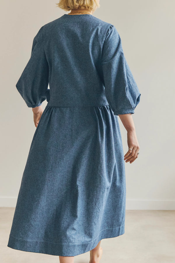 Person wearing a blue malie Wrap Dress made with PDF sewing pattern with puffed sleeves against a plain background