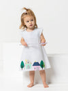 Child wearing a dress made using andie kids dress sewing patternwith house illustrations on a white background