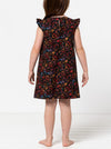 Child wearing a floral dress made using andie kids dress sewing pattern on a white background