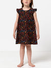 Young girl wearing a floral dress made using andie kids dress sewing patternon a white background