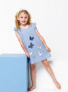 Young girl wearing a blue dress made using andie kids dress sewing patternwith butterfly patterns on a white background