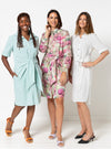 Three women wearing light blue, floral, and polka dot dresses made using Avon Woven Shirt and Dress sewing patternon a white background