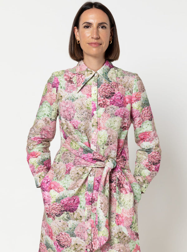 Woman wearing a floral dress made using Avon Woven Shirt and Dress sewing patternagainst a plain background