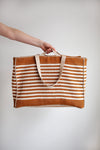 Striped tote bag with a hand made using the Away Tote PDF Sewing Patternholding it against a plain background