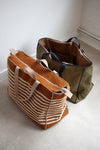 Two tote bags, one brown with white stripes and one green, made using the Away Tote PDF Sewing Patternon a light surface.