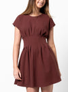Woman wearing a maroon dress made using Bronte Woven Dress sewing patternon a white background