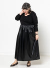 Woman wearing a black Carter Dress made using StyleArc pattern with tee bodice and mid-calf linen skirt with a white background