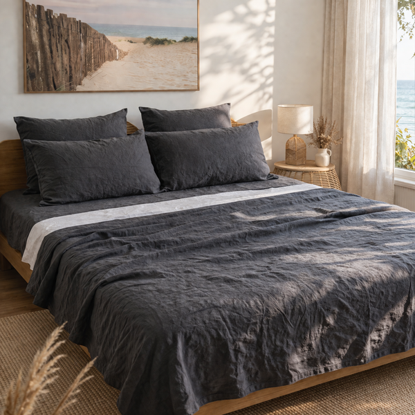 Bedroom with a bed covered in dark gray bedding, a lamp on a bedside table, and a painting on the wall.