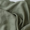 A close-up of draped Eucalypt Khaki linen fabric with a visible woven texture and soft folds.