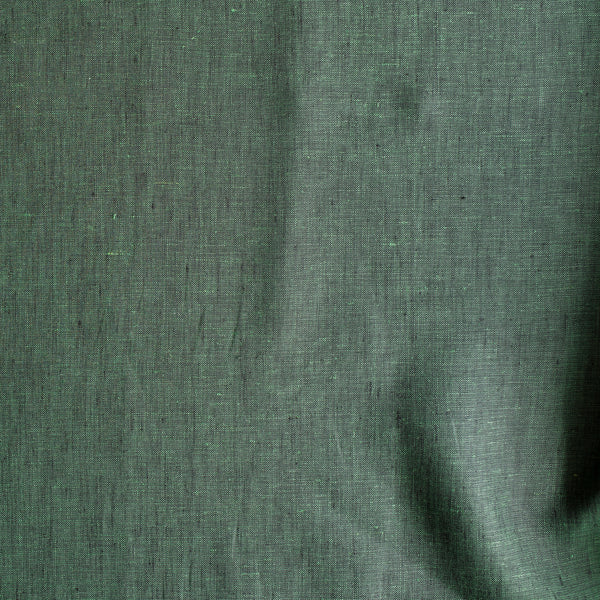 Close-up of Forest Chambray linen fabric in deep earthy green with green-and-black chambray weave, 100% linen, 160 GSM