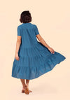 Woman wearing a blue Poppy Dress on a beige background