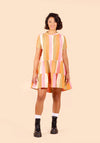 Woman wearing a colourful striped Poppy Dress on a beige background