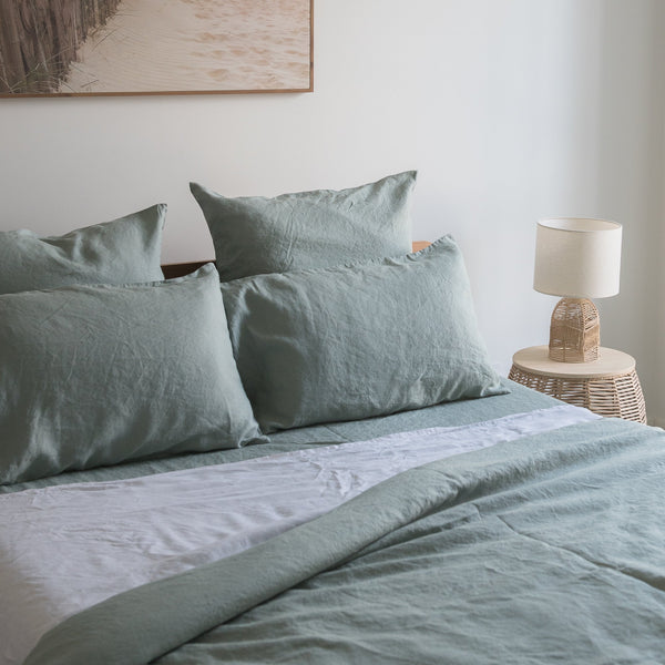 Bed with Harbour Sage flat sheet 100% linen bedding and pillows in a bedroom setting.