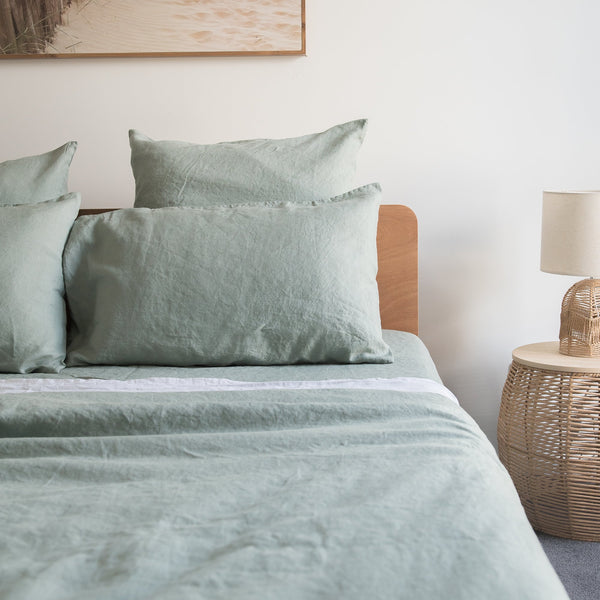 Bed with green bedding and Harbour Sage linen pillowcasesin a bedroom setting.