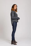 Woman wearing a gray sweater and blue jeans on a white background