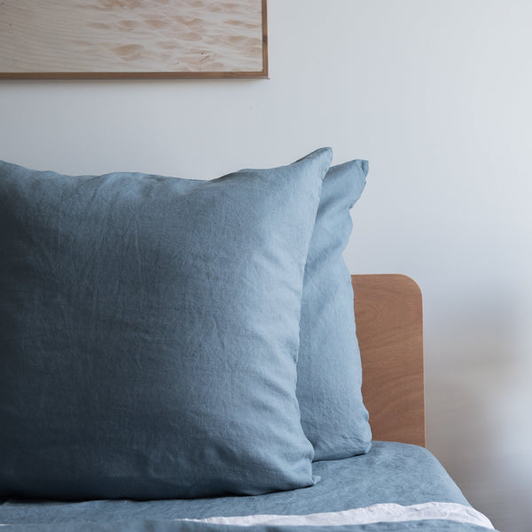 Lake Blue 100% Linen European Pillowcase on a bed with a neutral wall in the background