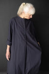 Person wearing a dark blue dress made using The Niven Sewing Pattern by Merchant & Millsagainst a black background