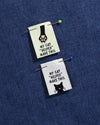 Two small fabric patches with cat illustrations and text on a blue background