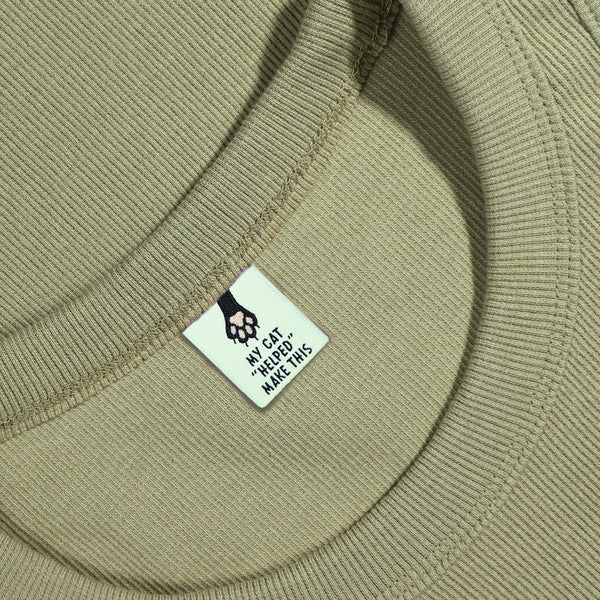 Close-up of a bgreen fabric with a label featuring a paw print design and text.