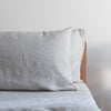 Natural linen flat sheet soft beige bedding pillow on a bed with a neutral background