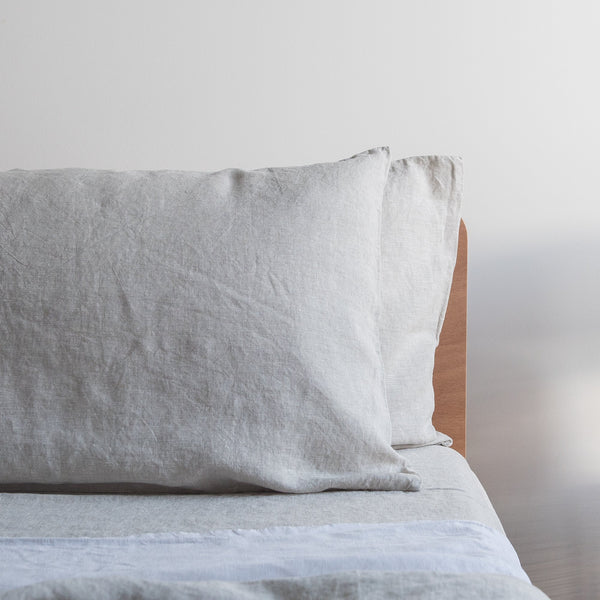 Natural linen flat sheet soft beige bedding pillow on a bed with a neutral background