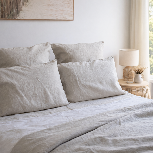 Neatly made bed with light-colored bedding and pillows in a bedroom setting.