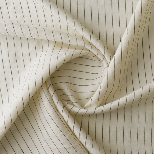 A close-up of draped cream-colored fabric with thin, evenly spaced vertical dark olive stripes, arranged in a central swirl to show texture and drape.