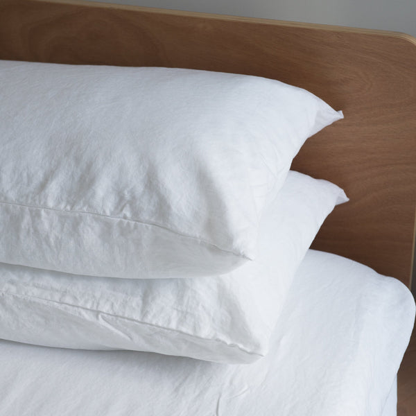Pure white European linen pillowcaseson a wooden headboard