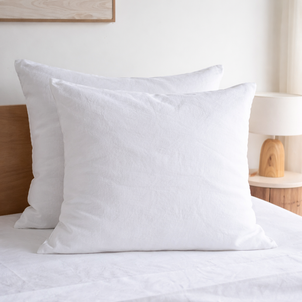 Two Pure white European linen pillowcaseson a bed in a bedroom setting.