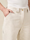 Beige pants made of Rika Pants sewing pattern in cropped tailored style with hem cuffs and tabbed waistbandwith a white top on a neutral background