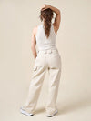 Woman wearing a white sleeveless top and cream-colored wide-leg pants against a beige background