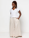 Woman wearing a white top and beige pants made using Rumi Top Sewing Pattern against a white background