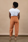 Person wearing a white top and orange pants made using Sepia Pants and Shorts sewing patternagainst a beige background