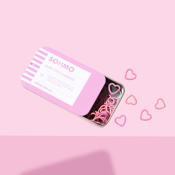 Pink tin with heart-shaped hair ties on a pink background