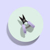 Pet nail clippers with purple handle on a light green circle against a light purple background