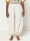 Person wearing white harem pants made using Sophia Woven Bubble Skirt and Pant sewing pattern and a colorful top on a plain background