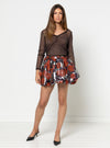Woman wearing a brown top and floral skirt made using Sophia Woven Bubble Skirt and Pant sewing pattern on a white background