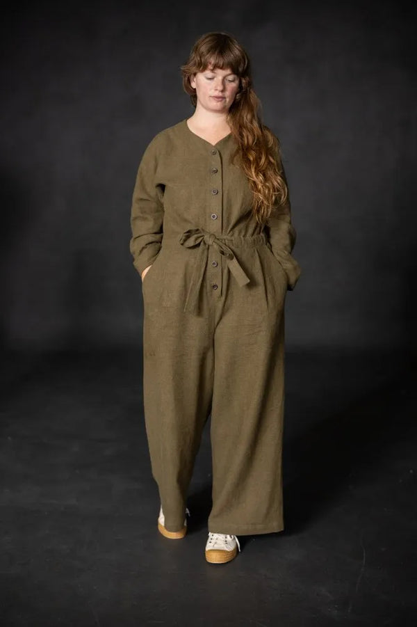 Woman wearing a green cassidy jumpsuit against a black background