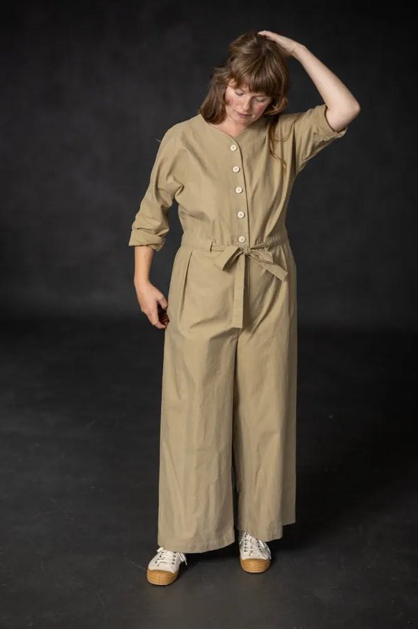 Woman wearing a beige cassidy jumpsuit against a black background