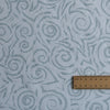 Textured fabric with spiral pattern and a wooden ruler for scale.