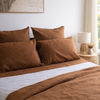 Tobacco brown bedding set on a bed with a lamp and decor in the background